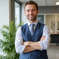 Profesional portrait of a friendly nutritionist, male, with a confident and approachable expression, wearing smart casual attire, in a bright, modern office with a plant in the background, natural background, no text.